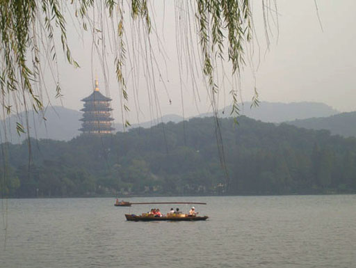 Boat with people on West Lake. A multi tiered pagoda is visible in the background.