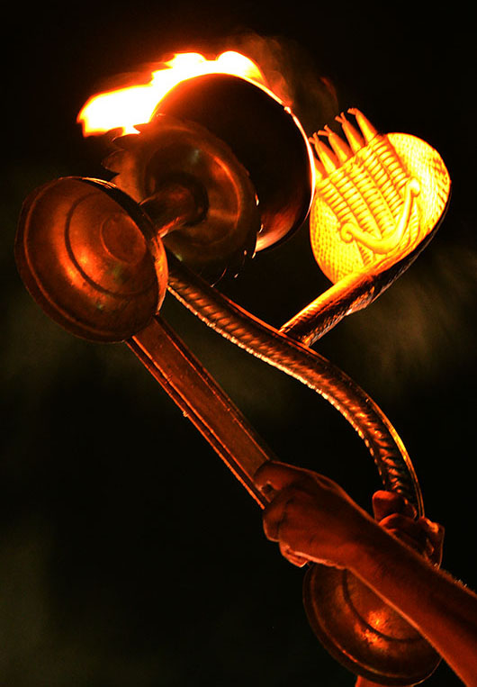 Close-up of Brass Aarti with Cobra hood held aloft by a temple priest.