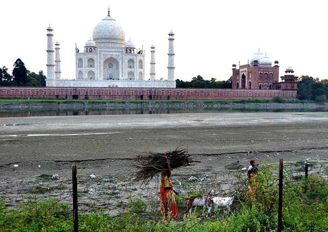 Conspicuous contrast! Poor villagers retuning homw along the dried up river bed