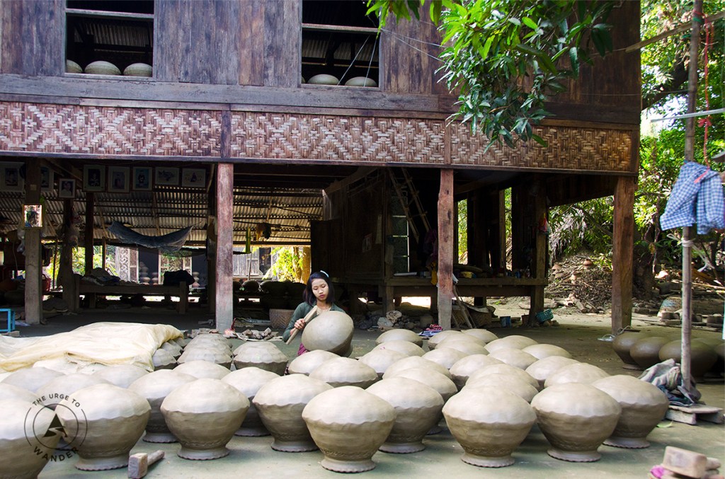 A young girl tests rows of overturned clay pots by tapping with a wooden stick in Yandabo