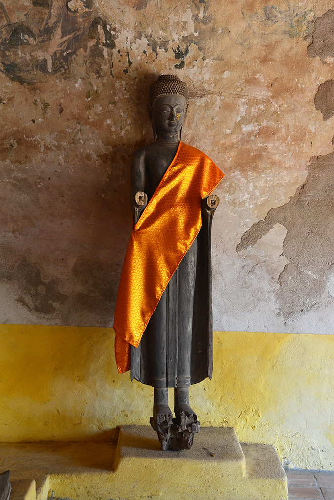 Exquisite wooden Buddha in Wat Sisaket with an orange brocade sash draped across one shoulder