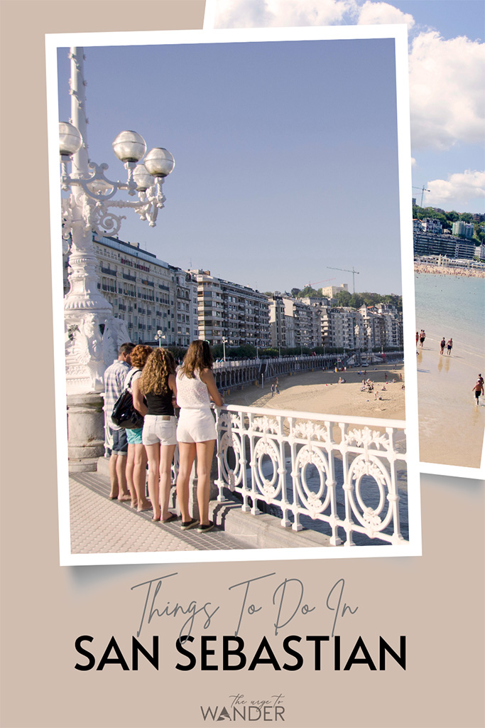 Three girls in shorts and a man in a checked shirt stand in front of the signature white railing above the Playa La Concha (beach).